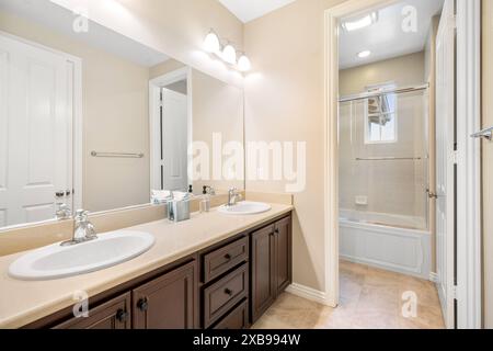 A bathroom with dual sinks, mirror, and tiled floor Stock Photo