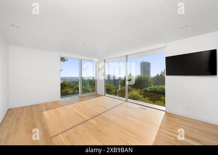 A modern bedroom with hardwood floors and a wall-mounted television Stock Photo