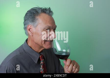 Mature Man smiling and enjoying a big glass of red wine Stock Photo