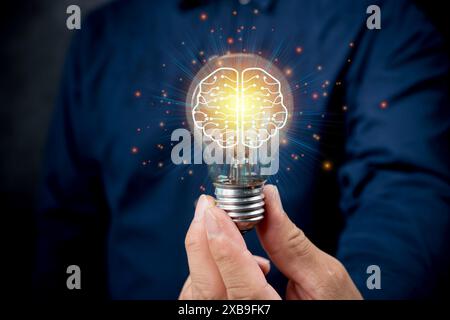 Businessman holding half of an abstract light bulb and brain on a dark blue background with a light bulb in the foreground. The concept of the busines Stock Photo