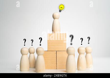 A group of wooden figures are arranged in a pyramid with one figure at the top and the rest below it. The pyramid is topped with a light bulb, which r Stock Photo