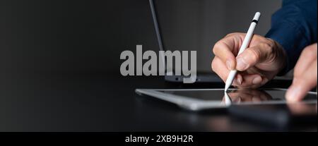 Businessman, manager using stylus pen signing e-document on digital tablet with laptop computer on table at modern office, e-signing, electronic signa Stock Photo