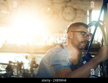 Bicycle technician, repair and working in shop with tyre, chain and tools for maintenance or cycling. Mechanic, bike and fixing in workshop as Stock Photo