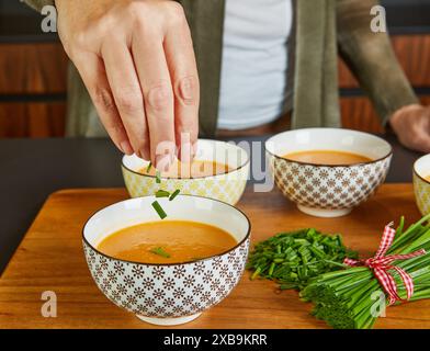 The chef adds green onions to the Boiled Cream Soup in serving bowls. Stock Photo