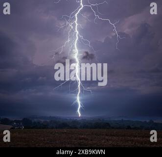 A dramatic lightning bolt striking down during a thunderstorm over a rural landscape. Lewisburg Stock Photo