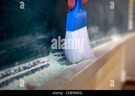 Chalkdust brush cleaning the chalk dust on the blackboard or chalkboard Stock Photo