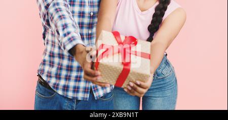 Teenage couple rejoicing, stretching present box to camera Stock Photo