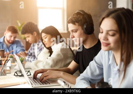 Diverse group of students studying with tech in library Stock Photo