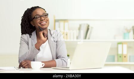 Dreamy African American businesswoman sitting at her office Stock Photo