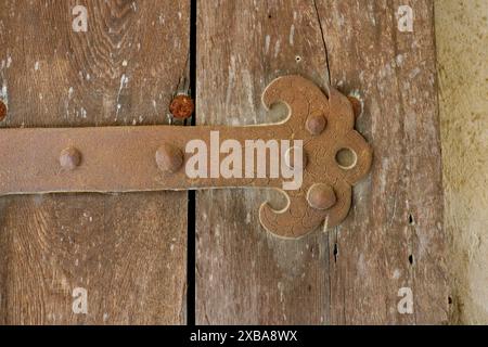 A forged iron band as a door hinge on a medieval wooden door. detail shot. Stock Photo