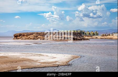 Lac Assal salt lake waters with salt extraction factory in the background, the lowest point of Africa, Tadjourah Region, Djibouti Stock Photo