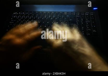 man hands typing at night on backlit PC keyboard Stock Photo