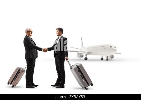 Businessmen with suitcases shaking hands at the airport isolated on white background Stock Photo