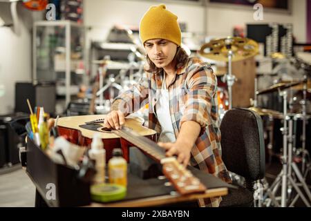 Guy repairing electric guitar in a music instrument workshop Stock Photo