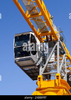 Construction tower crane cabin, isolated on clear blue sky background, low angle perspective shot. Stock Photo