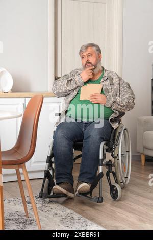 Portrait of sad senior veteran in wheelchair with letters at home Stock Photo