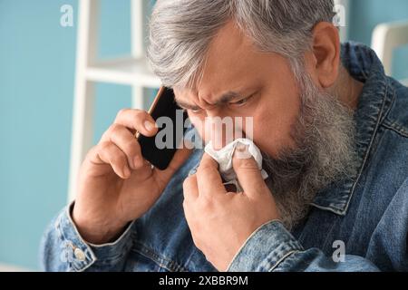 Portrait of crying senior man talking by phone at home, closeup Stock Photo