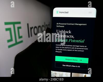 Person holding cellphone with webpage of US contract management software company Ironclad Inc. in front of logo. Focus on center of phone display. Stock Photo