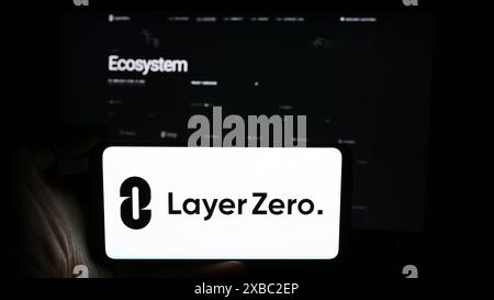 Person holding cellphone with logo of Canadian blockchain company LayerZero Labs Ltd. in front of business webpage. Focus on phone display. Stock Photo