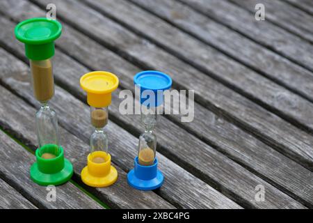 Three hourglasses on rustic weathered wooden table. Time is running Stock Photo