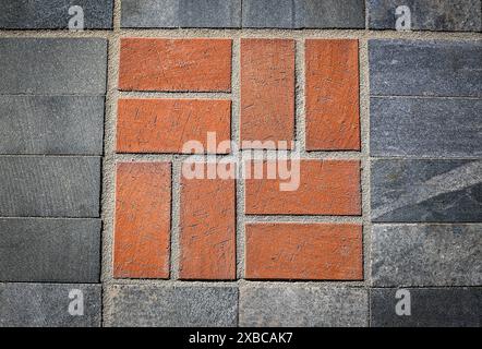 Geometric pattern with red bricks surrounded by grey concrete tiles, background image Stock Photo