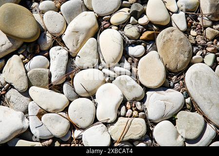 A collection of beige and grey pebbles and stones forming a natural texture, background image Stock Photo