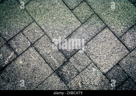 Gray concrete tiles arranged in a geometric pattern creating a rough and textured surface, background image Stock Photo