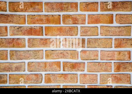 A close-up view of a brick wall with red and orange bricks, showcasing a rough texture and detailed pattern, background image Stock Photo