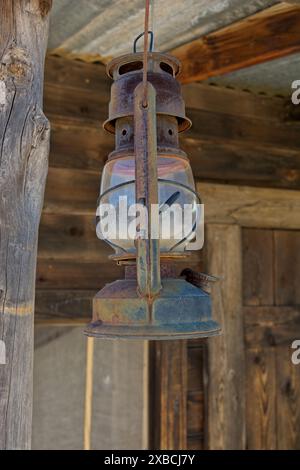 Rusty miners lamp hanging from rafter on rustic wood portico Stock Photo