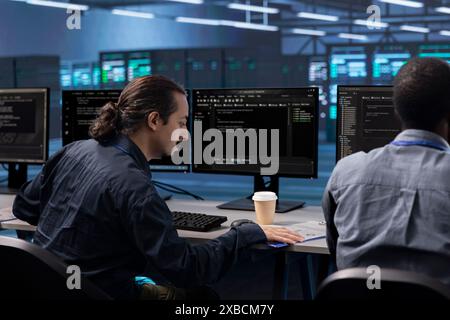 Coworkers in data center workspace running system diagnostic tests to do repairments. IT experts at PC desk in server hub deploying error checking utilities to fix network issues Stock Photo