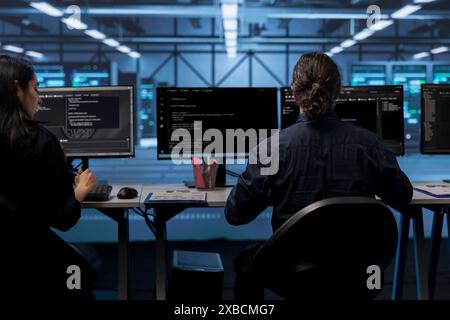 Computer operators in data center running system diagnostic tests to do repairments. IT specialists at PC desk in server room deploying error checking utilities to fix network issues Stock Photo