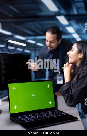 Focus on isolated screen laptop used by system administrators in blurry background to oversee supercomputers. Close up shot of chroma key notebook used by IT expert in server hub establishment Stock Photo