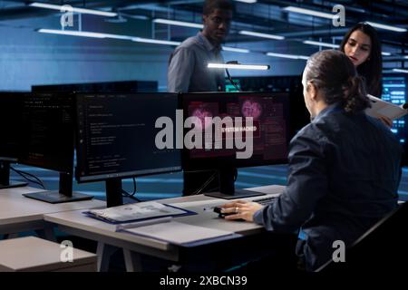 Computer scientist in server hub calling coworkers for help, trying to protect equipment from hacker. IT specialist in data center facility requesting assistance to fix security breach alert Stock Photo