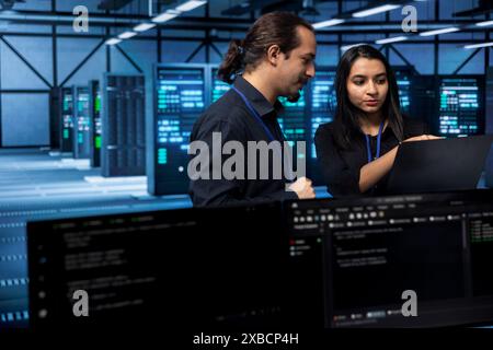 Software developers in data center running system diagnostic tests on laptop to fix problems. IT staff members deploying and error checking utilities on notebook to fix network issues performance Stock Photo
