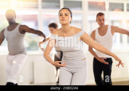 Young Asian woman practicing basic ballet movements at group class Stock Photo