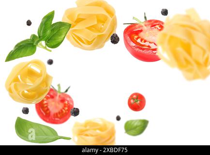 Raw pasta, tomatoes and basil in air on white background Stock Photo