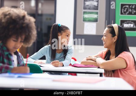 In school, in classroom, biracial female teacher watches students ...