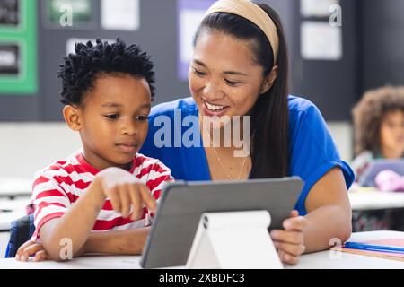 Biracial teacher showing African American student something on tablet Stock Photo