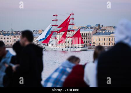 St. Petersburg, Russia. 11 June, 2024. People watch the Brig 'Russia', a two-masted ship symbol of the Scarlet Sails graduates holiday, sailing along the Neva River against the backdrop of the Kutuzov embankment during a rehearsal for the holiday. The Scarlet Sails holiday is a traditional grand event that takes place annually in St. Petersburg to celebrate the graduation of students from higher educational institutions. Credit: SOPA Images Limited/Alamy Live News Stock Photo