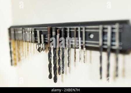 A row of various drill bits neatly organized on wall-mounted rack. White background showing a clean, well-lit prosthetic lab with white walls and orga Stock Photo