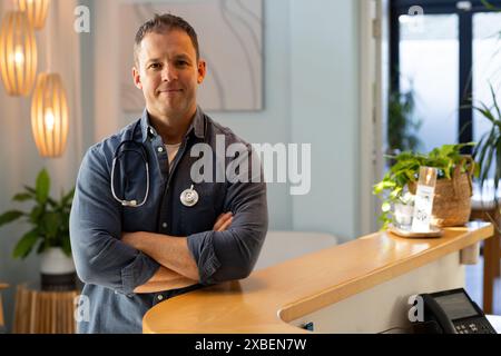 Middle-aged Caucasian male doctor in reception with a stethoscope around his neck. He is in a modern prosthetic lab with plants and soft lighting in b Stock Photo