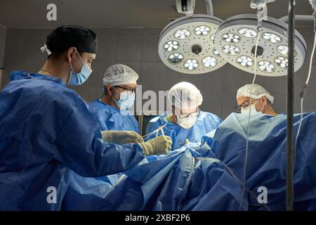 Surgeons performing an operation in a sterile surgical room Stock Photo