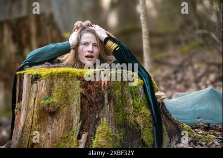 A woman is trapped in a tree stump in a forest. Shallow depth of feld Stock Photo