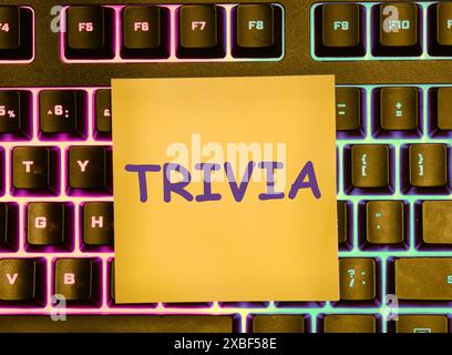 Finance and economics concept. The text is written - TRIVIA on a yellow sticker lying on the keyboard with a colored backlight Stock Photo