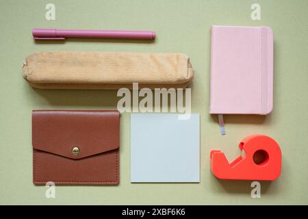 Various office and school supply. pen, pencil case, card wallet, memo pad, notebook, tape dispenser on khaki desk background. top view Stock Photo