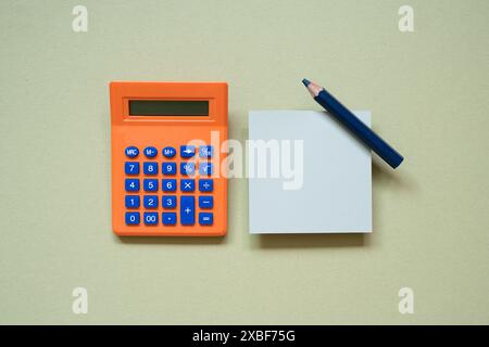 Orange calculator and memo pad, pencil on khaki desk background. top view Stock Photo