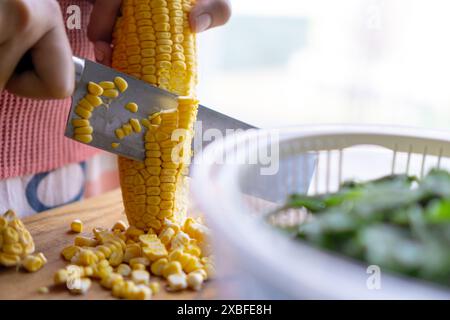 woman cutting corn in the wooden board, home cooking concept Stock Photo
