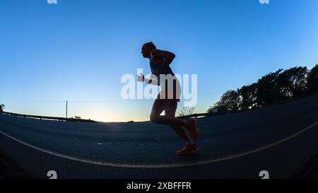 Ultra Distance Runner Marathon runners silhouetted morning dawn sunrise running up hill in ...
