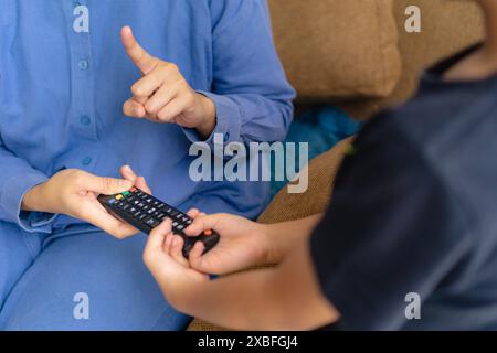 mother and son holding remote tv, saying no to his son over watching television, concept of parenting Stock Photo
