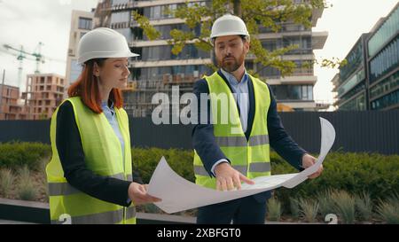 Two contractors civil engineers discuss electrical maintenance blueprint paper partnership discuss teamwork city buildings project construction Stock Photo